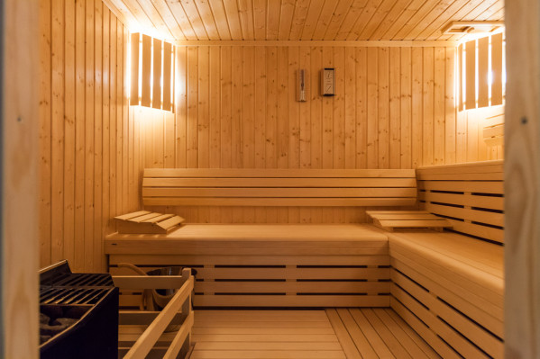 Innenansicht einer Sauna im 'Baltic Spa' des Campingplatzes mit hellem Holz, beleuchteten Lamellen und Sitzbänken.