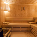 Innenansicht einer Sauna im 'Baltic Spa' des Campingplatzes mit hellem Holz, beleuchteten Lamellen und Sitzbänken.