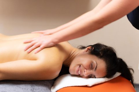 Frau genießt eine entspannende Rückenmassage in einem Wellnessbereich des Campingplatzes.