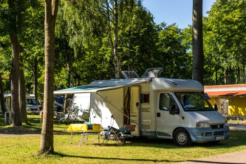 Wohnmobil geparkt unter Bäumen auf dem Campingplatz Baltic Freizeit in Markgrafenheide.