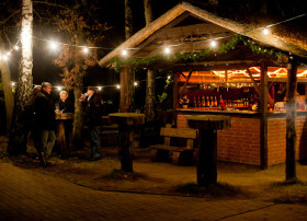 Weihnachtlich geschmückte Hütte mit Beleuchtung und Glüchwein trinkenden Campern auf dem Campingplatz Baltic Freizeit in Markgrafenheide.