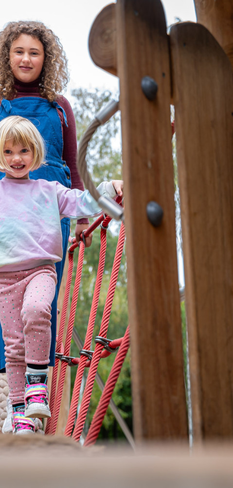 Zwei Kinder klettern auf einer Brücke auf einem Spielplatz auf dem Campingplatz baltic freizeit in Markgrafenheide.