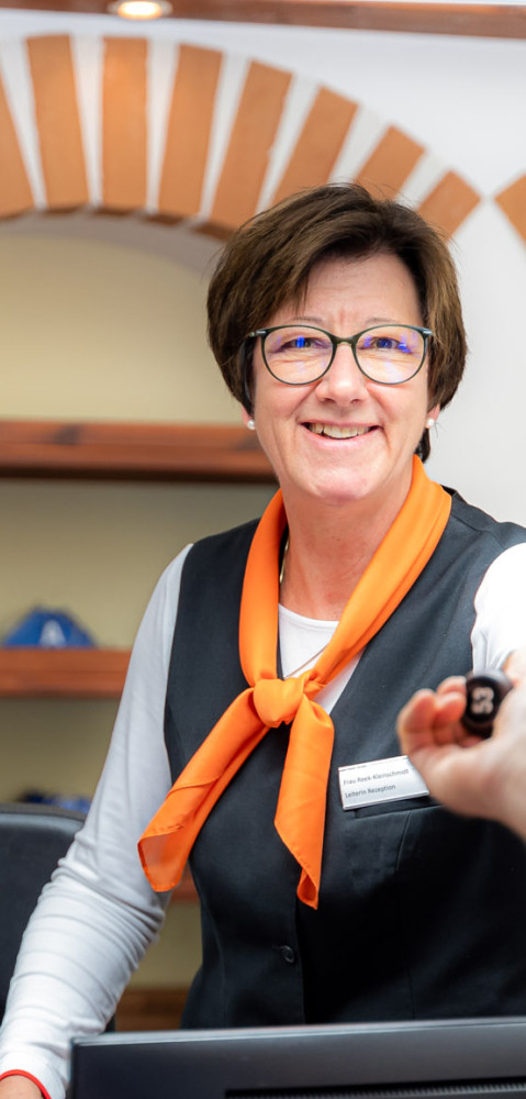 Frau mit Brille übergibt Schlüssel für ein Ferienhaus auf dem Campingplatz von baltic freizeit.