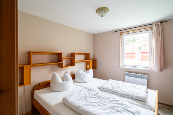 Helles Innenzimmer mit Doppelbett, Holzregalen und Fensterblick im Campingplatz Baltic Freizeit Markgrafenheide.