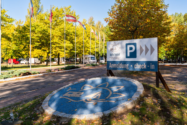 Eingangsbereich von Baltic Freizeit mit Check-in-Schild, Flaggen und Mosaik am Boden.