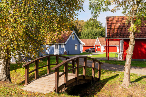 Holzbrücke vor farbenfrohen Hütten im Herbst bei Baltic Freizeit Campingplatz.