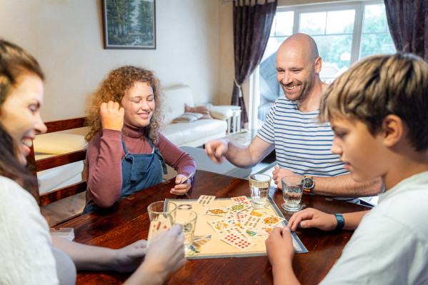 Familie spielt gemeinsam ein Brettspiel in einem gemütlichen Wohnraum bei Baltic Freizeit in Markgrafenheide.