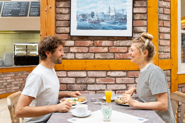 Pärchen sitzt sich lächelnd gegenüber und frühstückt im Restaurant auf dem Campingplatz.