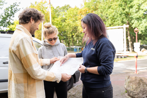 Mitarbeiterin erklärt anreisenden Campern den Lageplan auf dem Campingplatz von Baltic Freizeit.