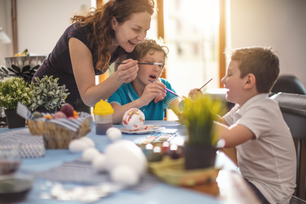 Kinder und Erwachsene bemalen fröhlich bunte Ostereier