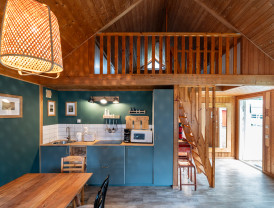 Innenansicht einer stilvoll gestalteten Küchenecke mit blauen Schränken, weiß gefliestem Spritzschutz und hölzernem Dach bei Baltic Freizeit in Markgrafenheide.