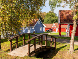 Holzbrücke vor farbenfrohen Hütten im Herbst bei Baltic Freizeit Campingplatz.