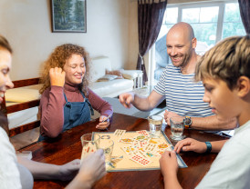 Familie spielt gemeinsam ein Brettspiel in einem gemütlichen Wohnraum bei Baltic Freizeit in Markgrafenheide.