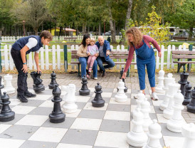 Junge Familie mit Kindern spielt Schach auf einem großen Feld im Außenbereich auf dem Campingplatz von Baltic Freizeit.