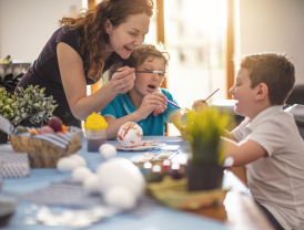 Kinder und Erwachsene bemalen fröhlich bunte Ostereier