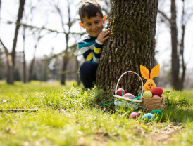 Junge entdeckt bunte Ostereier in Körben am Baum