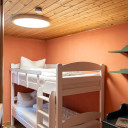 Kinderzimmer mit weißem Etagenbett, orangefarbener Wand und Holzdecke im Campingplatz Baltic Freizeit Markgrafenheide.