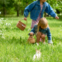 Zwei Kinder sammeln Ostereier, weißes Kaninchen im Gras