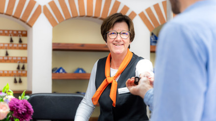 Frau mit Brille übergibt Schlüssel für ein Ferienhaus auf dem Campingplatz von baltic freizeit.